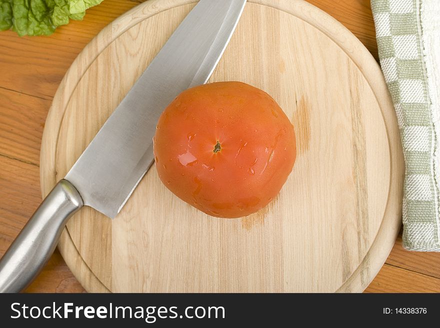 Red tomatoes on a wooden board near a knife