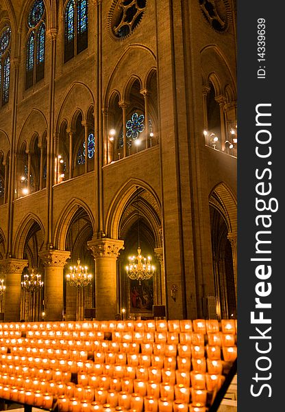 A bank of  glowing prayer candles inside of Notre Dame Cathedral in Paris, France. A bank of  glowing prayer candles inside of Notre Dame Cathedral in Paris, France