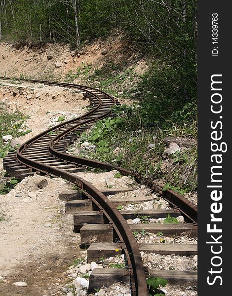 Old Winding Railway Tracks with stones and sand in the Summer Forest