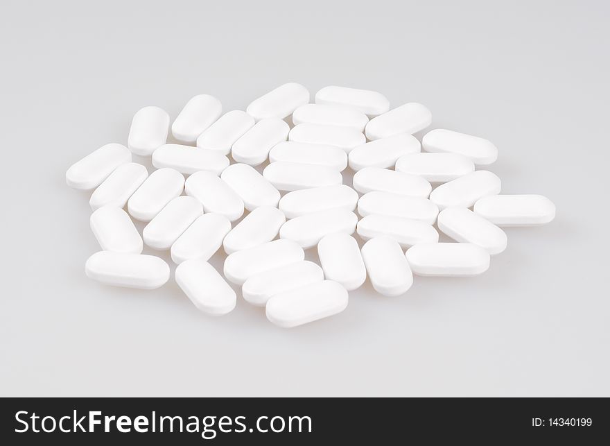 White pills lying on a light background. Close-up.