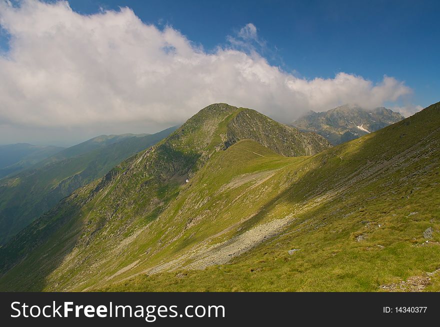 Mountain landscape view from Carpati Mountains, Romania. Blue sky with fluffy white clouds.