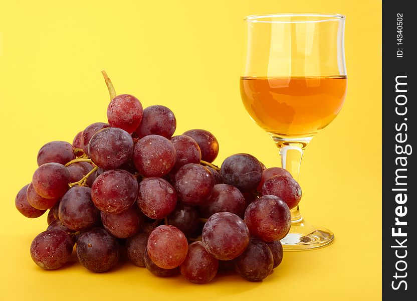 Branch of grape with wineglass on yellow background