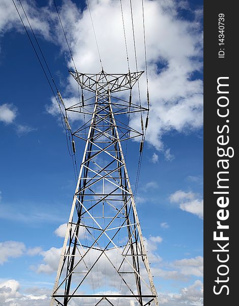 A steel electricity pylon against a blue sky with white coulds