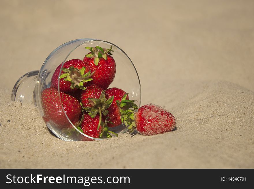 Ripe red strawberries in a glass on the sand. Ripe red strawberries in a glass on the sand