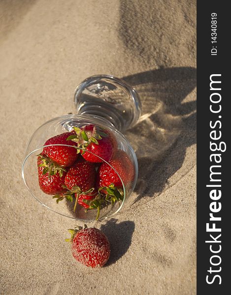 Ripe red strawberries in a glass on the sand. Ripe red strawberries in a glass on the sand