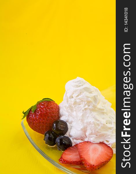 Strawberries and blueberries with whipped cream on glass plate. Strawberries and blueberries with whipped cream on glass plate