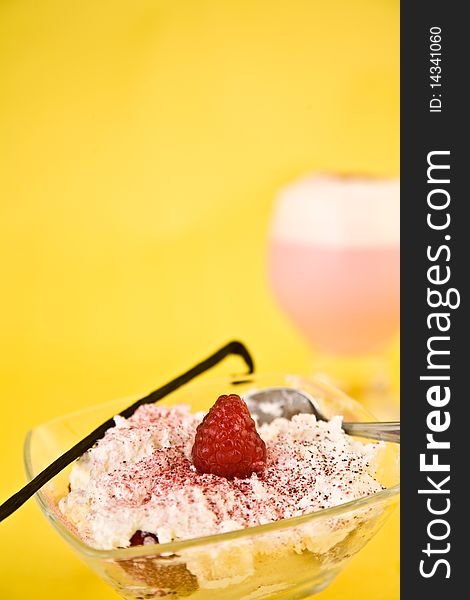 Whipped cream with strawberry and sprinkles in glass dish against yellow background. Whipped cream with strawberry and sprinkles in glass dish against yellow background