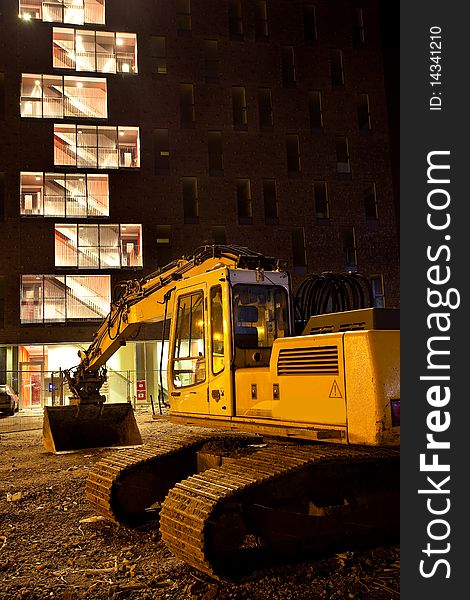 Excavator crane in front of building at night