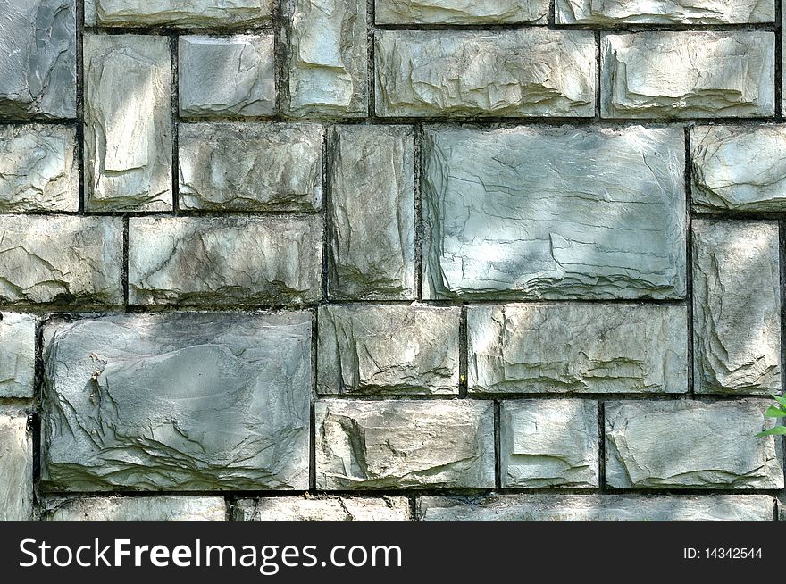 Texture and color of a stone wall surface under soft light and shadow, outdoor. Texture and color of a stone wall surface under soft light and shadow, outdoor.