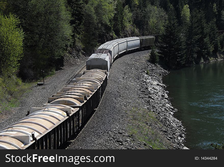 Train on tracks by river in forest