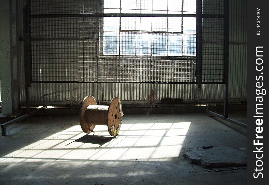 The sunlight shines down on an empty wire spool.