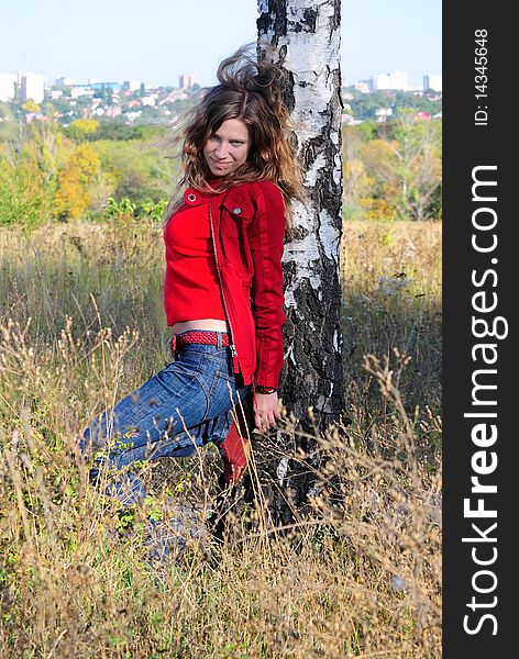 The girl leans against a birch and looks forward. The girl leans against a birch and looks forward