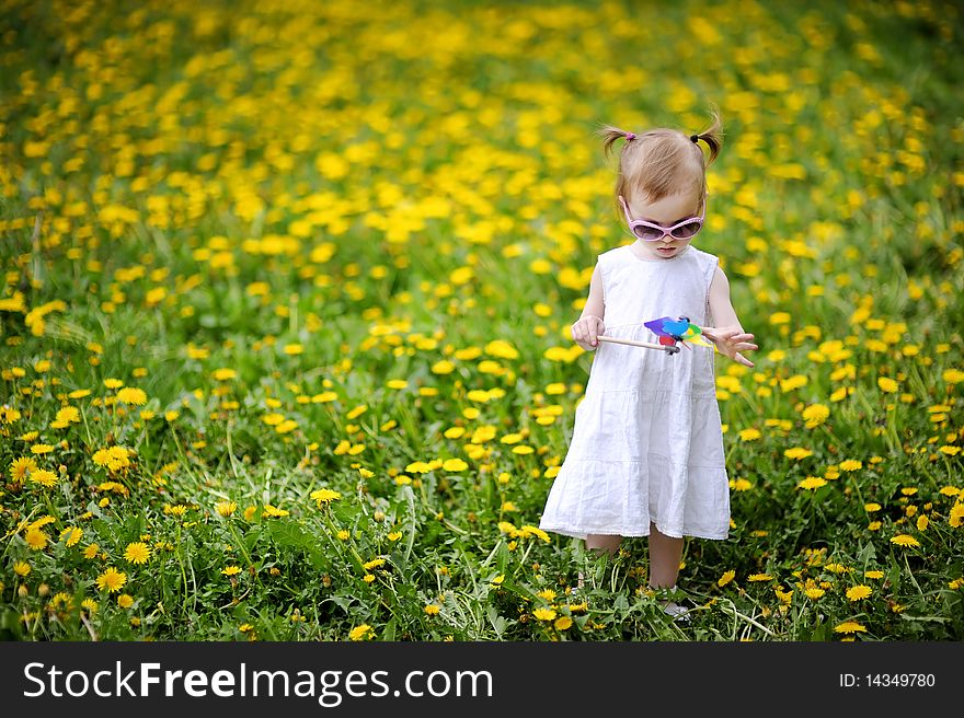 Adorable toddler girl standing in dandelions field. Adorable toddler girl standing in dandelions field