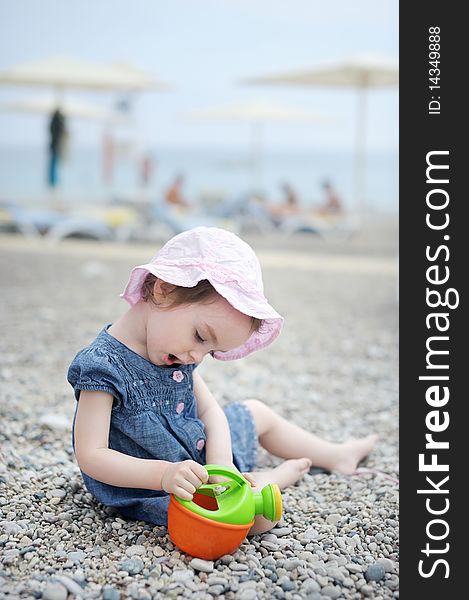 Adorable toddler girl plaiyng on a pebble beach. Adorable toddler girl plaiyng on a pebble beach