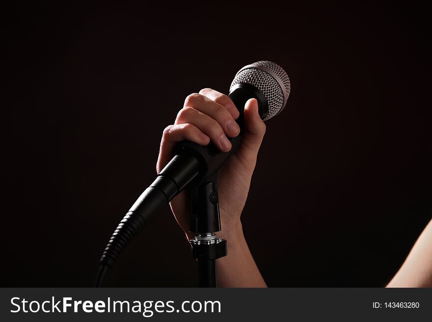 Woman holding microphone on black background, closeup