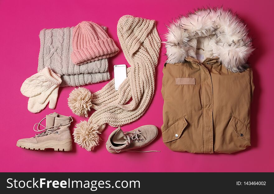 Flat lay composition with warm clothes for winter vacation on color background