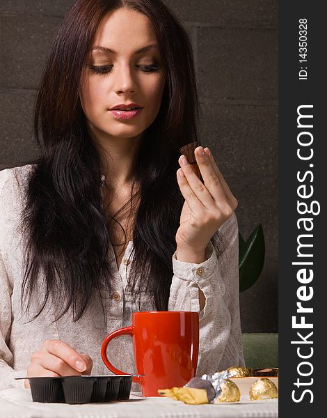 Beautiful lady drinking tea with chocolate candies