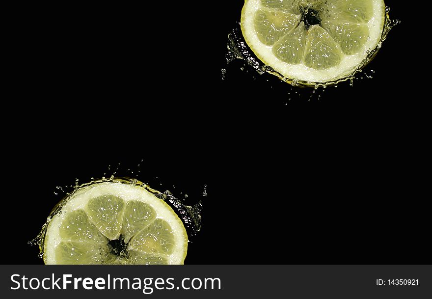 Lemon slice in water splashes on a black background