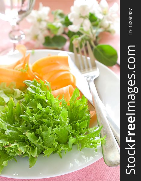 Salad from fresh vegetables for dinner. On a background a glass with water. A photo on a pink background