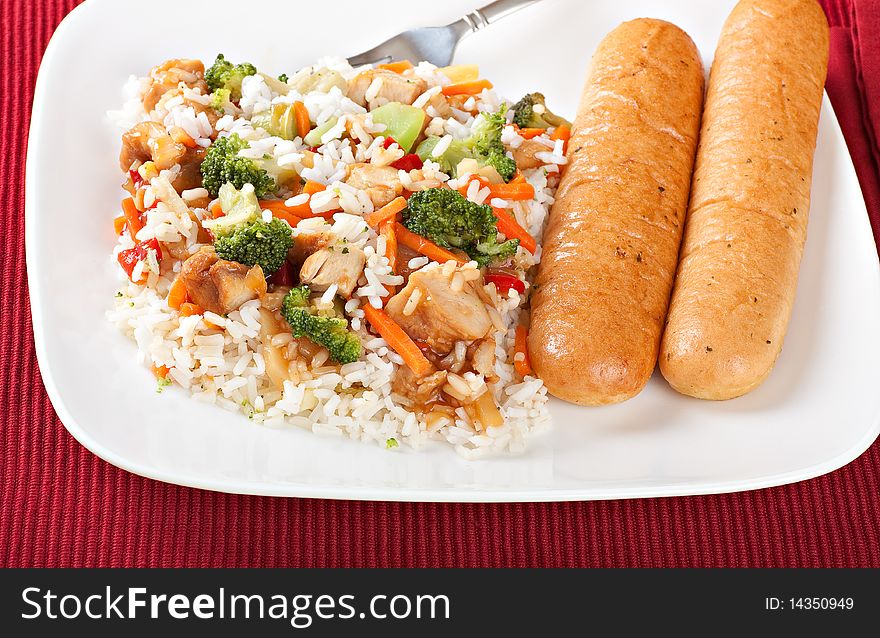 Chicken teriyaki over rice with bread sticks on a plate