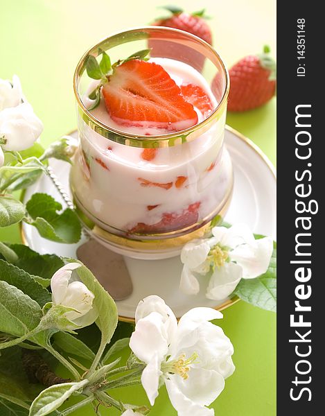 Strawberry yogurt with fresh strawberry in glass. On a 
green background