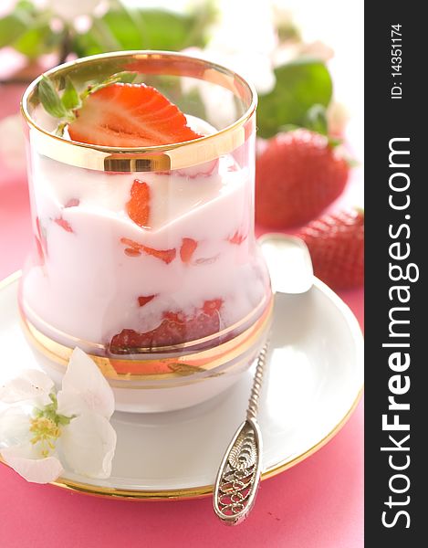 Strawberry yogurt with fresh strawberry in glass. On a pink background
