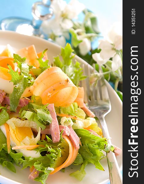 Salad from fresh vegetables for dinner. On a background a glass with water. A photo on a blue background. Salad from fresh vegetables for dinner. On a background a glass with water. A photo on a blue background