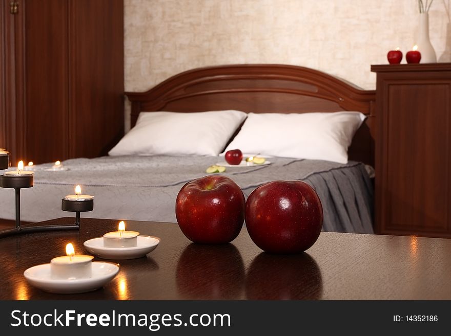 Little table in a bedroom , decorated with burning candles and apples