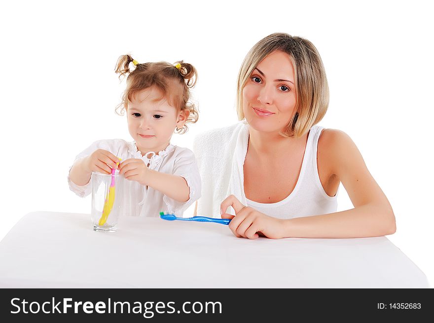 Young mother and her young daughter brush their teeth on a white background