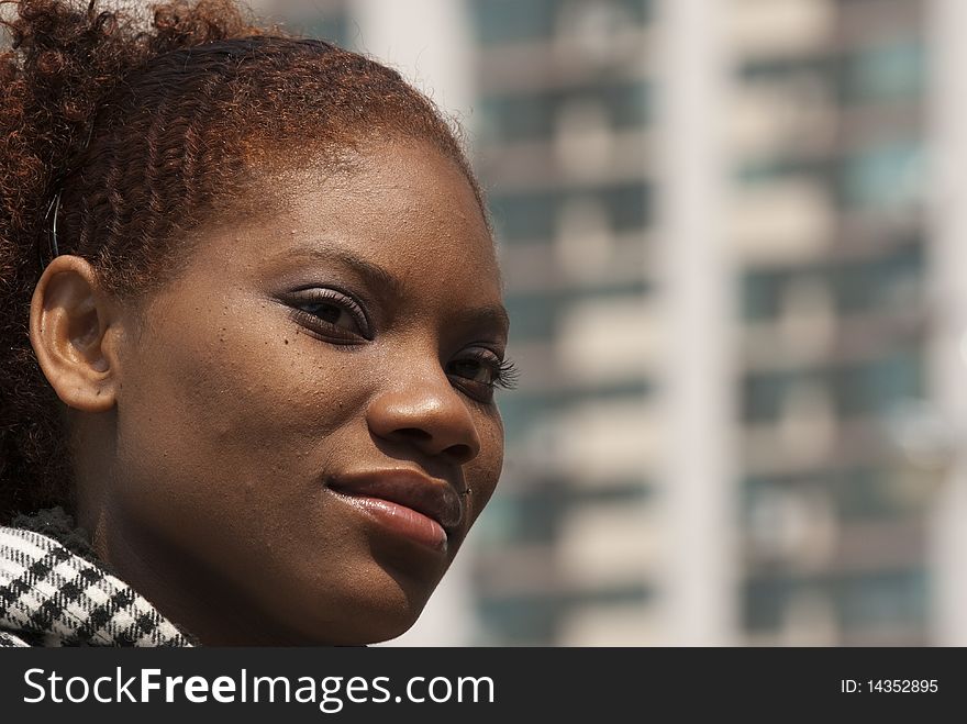 Head shot of an African-American woman outdoors with apartments in the background. Head shot of an African-American woman outdoors with apartments in the background