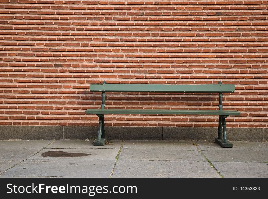 Green bench in front of brick wall. available also with EUROPEANS ONLY written on it