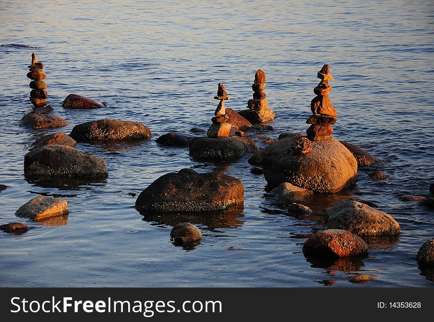 Balanced rock statues in the water at sunset.