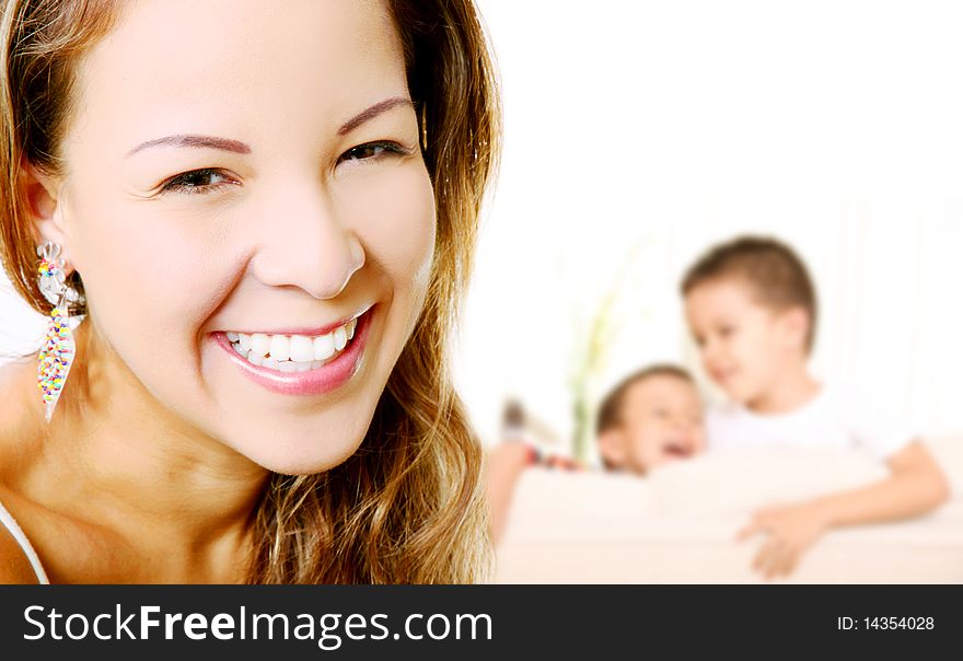 Young mother smiling and looking at the camera, In the background the children playing. Young mother smiling and looking at the camera, In the background the children playing