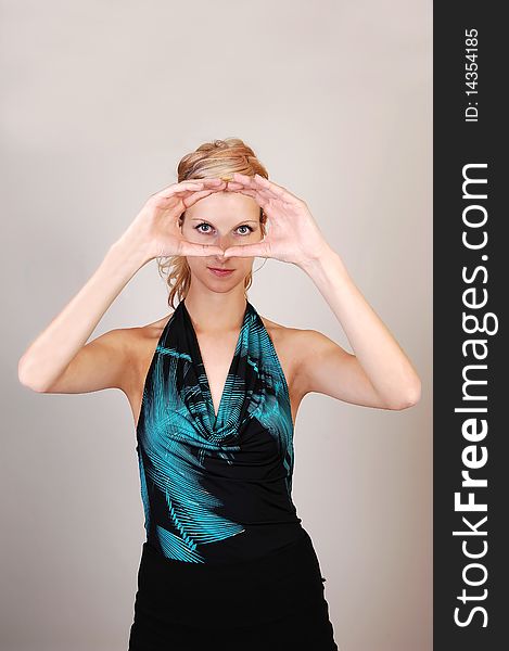 A beautiful blond woman holding her hands before her eyes and making
a sign, like a photographer, what the picture will look like, over light gray
background. A beautiful blond woman holding her hands before her eyes and making
a sign, like a photographer, what the picture will look like, over light gray
background.