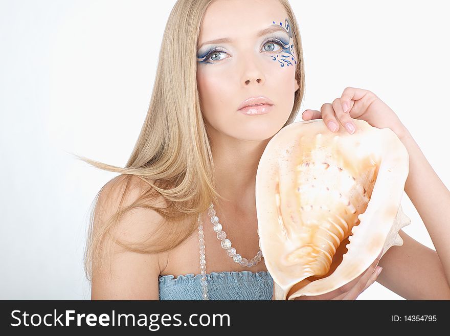 A girl with a seashell in his hands, with a sea of art makeup