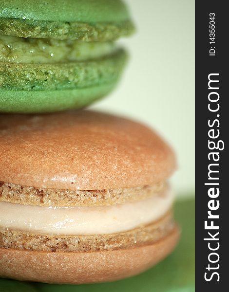 Pistachio and lemon French macaron close up on a green background. Pistachio and lemon French macaron close up on a green background