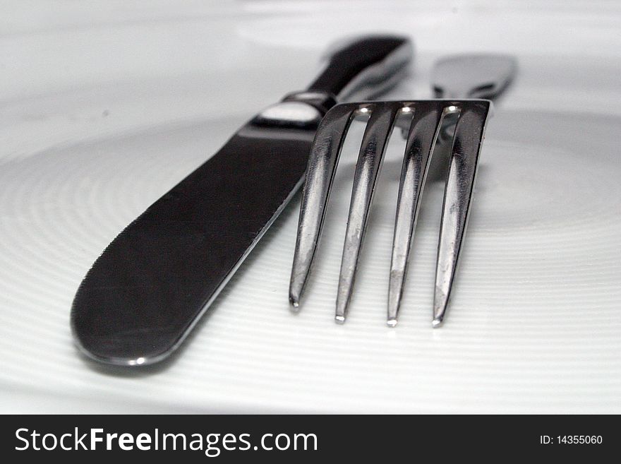 A fork and a knife on white dish. A fork and a knife on white dish