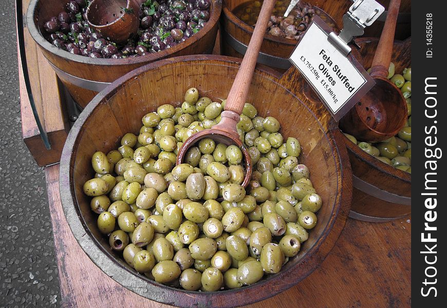 Green olives on a wooden pot background