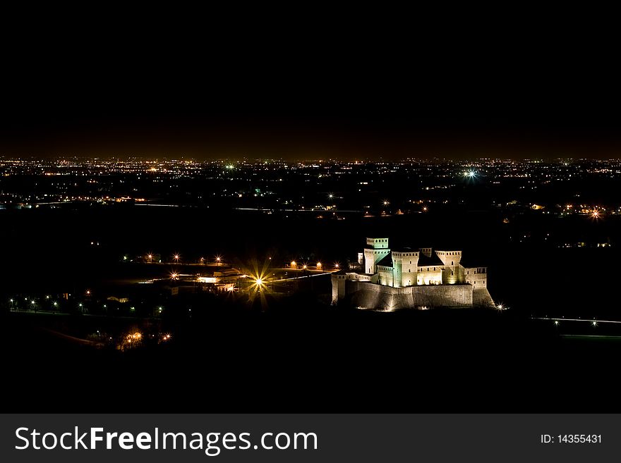 Torrechiara Castle by night, with the city of Parma in the background