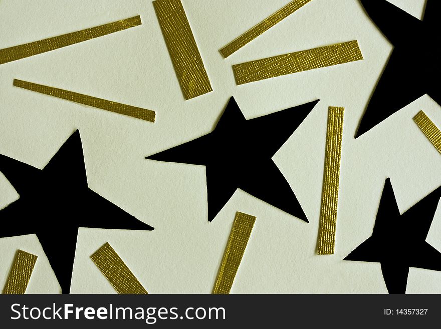 Cutouts of black stars and golden lines on white paper. Cutouts of black stars and golden lines on white paper