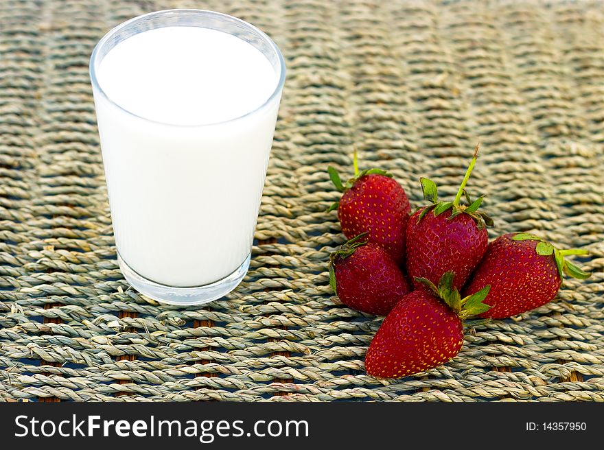 A glass of milk and strawberries in a wicker background