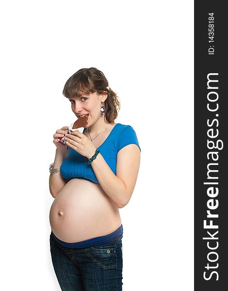 Pretty pregnant girl is eating chocolate and smiling. Pretty pregnant girl is eating chocolate and smiling