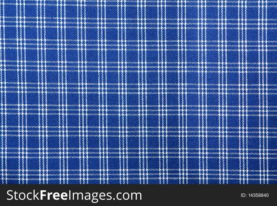 Blue textile with white crossing lines to form a squared pattern. Blue textile with white crossing lines to form a squared pattern