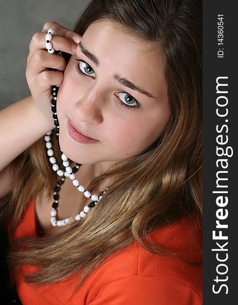 Beautiful teenage female wearing an orange top with necklaces