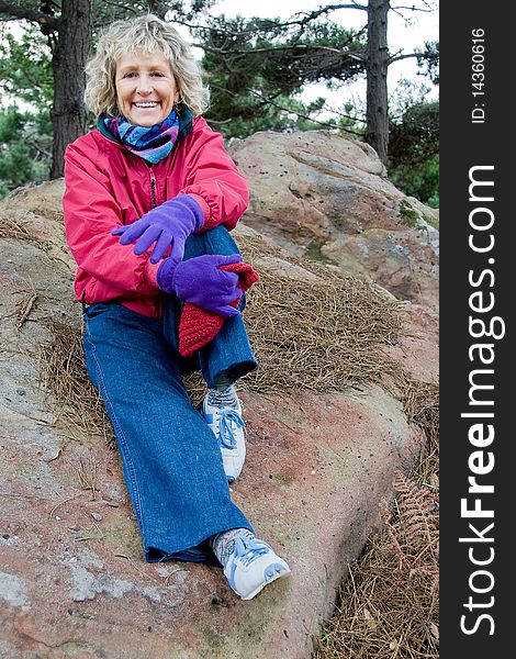 This shot of a senior woman sitting on a rock was taken in natural light on an overcast day. This shot of a senior woman sitting on a rock was taken in natural light on an overcast day.