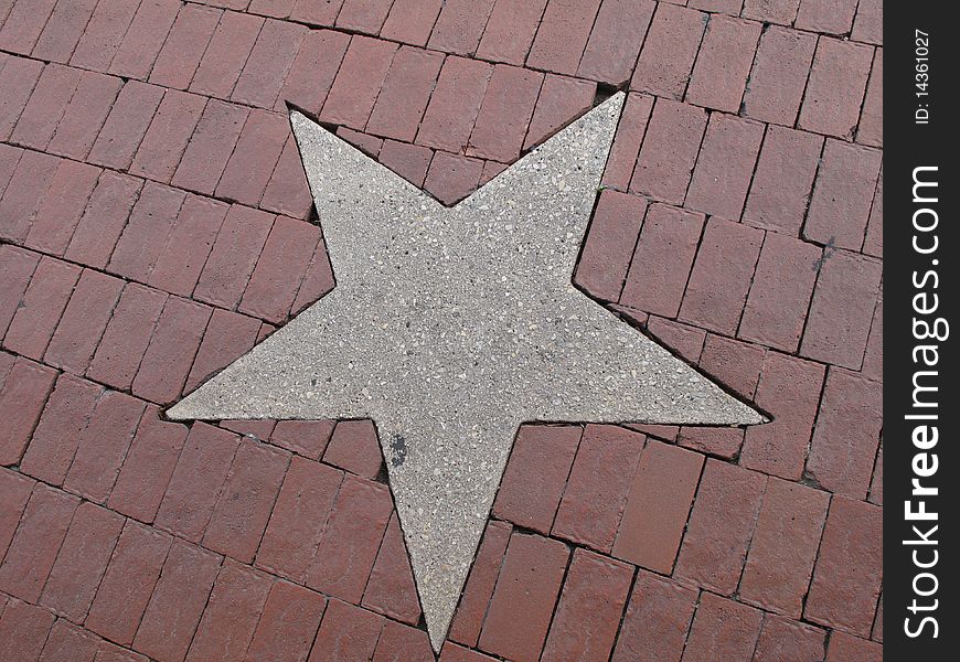 A concrete star in the middle of a cobblestone sidewalk. A concrete star in the middle of a cobblestone sidewalk.