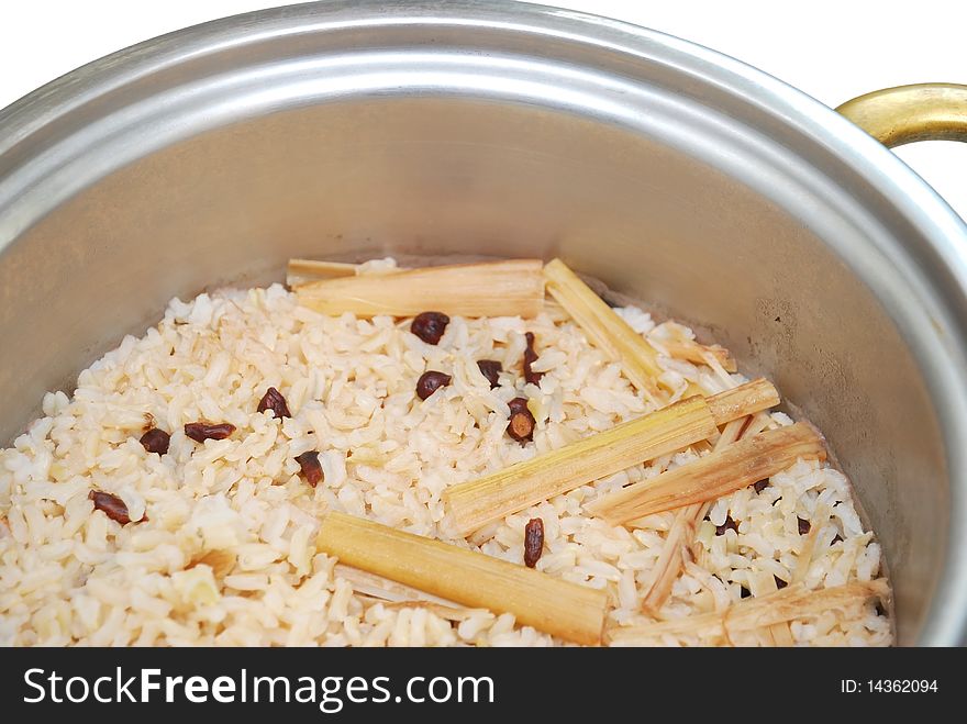 Healthy unpolished red rice and beans in rice pot isolated on white background. Suitable for concepts such as diet and nutrition, healthy lifestyle, and food and beverage.