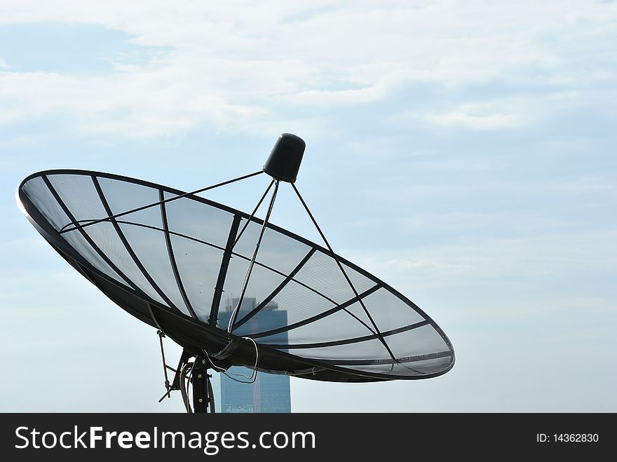 Satellite dish on rooftop and blue sky.