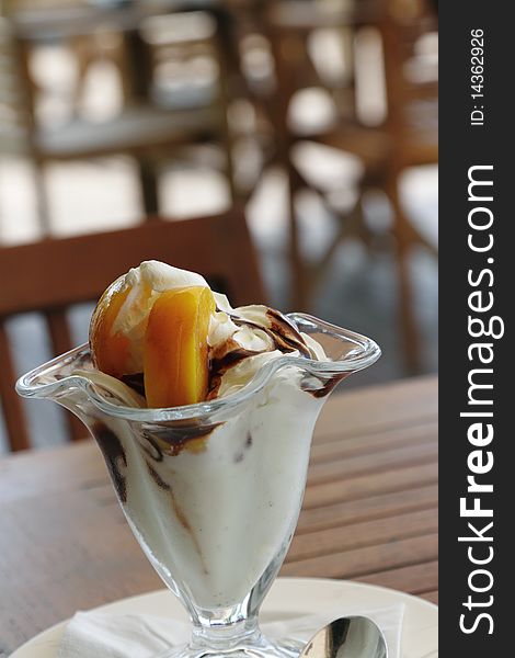 A cup of ice cream with peach and chocolate sauce. A cup of ice cream with peach and chocolate sauce