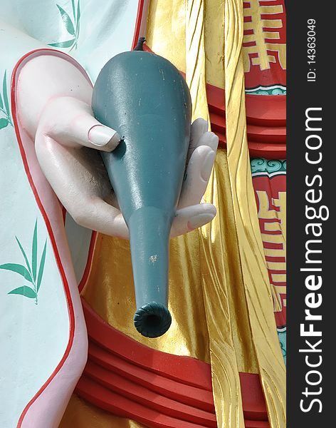 Close-up hand holding bottle of kuan yin statue in temple,thailand.female bodhisattva.